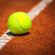 Pallina da tennis su campo in terra rossa