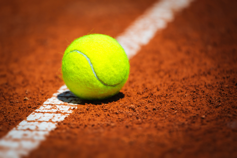 Pallina da tennis su campo in terra rossa