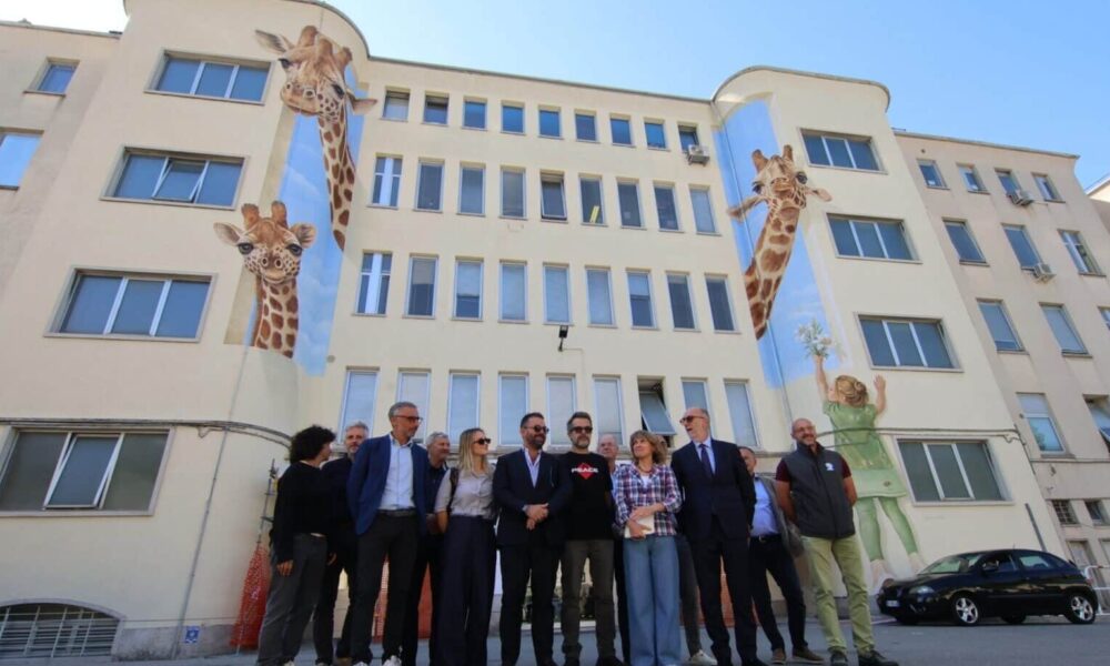 Foto di gruppo davanti al nuovo murales realizzato sulla facciata principale dell'Irccs materno infantile Burlo Garofolo di Trieste