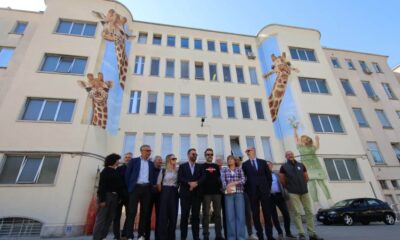 Foto di gruppo davanti al nuovo murales realizzato sulla facciata principale dell'Irccs materno infantile Burlo Garofolo di Trieste